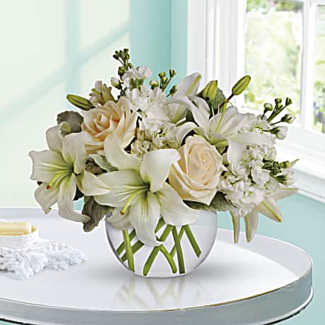 Isle of White - Like a vacation for the senses this lovely bouquet delivers an oasis of beauty and elegance. Soothing serene and very special. Cr?me roses white asiatic lilies and stock stem are incredibly arranged in a bubble vase. When it comes to bouquets this is definitely the right way to do white.  The bouquet pictured reflects our original design for this product. While we always try to follow the color palette, we may replace stems to deliver the freshest bouquet possible, and we may sometimes need to use a different vase.  