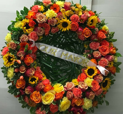 Warm Wreath Warm Wreath - Sunflowers, orange & yellow roses, warm accents and surrounding greenery.