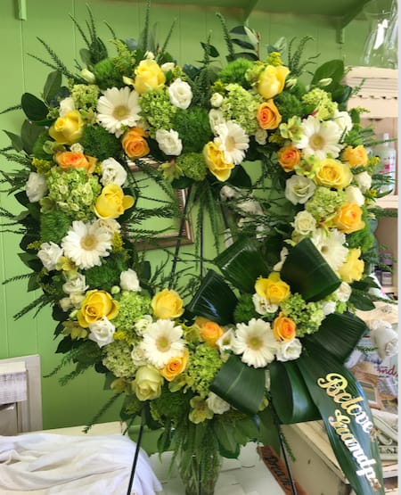 Deepest Affections Deepest Affections - A heart shaped eye catching standing spray detailed with bright orange & yellow roses, green hydrangeas, white roses, and daisies.