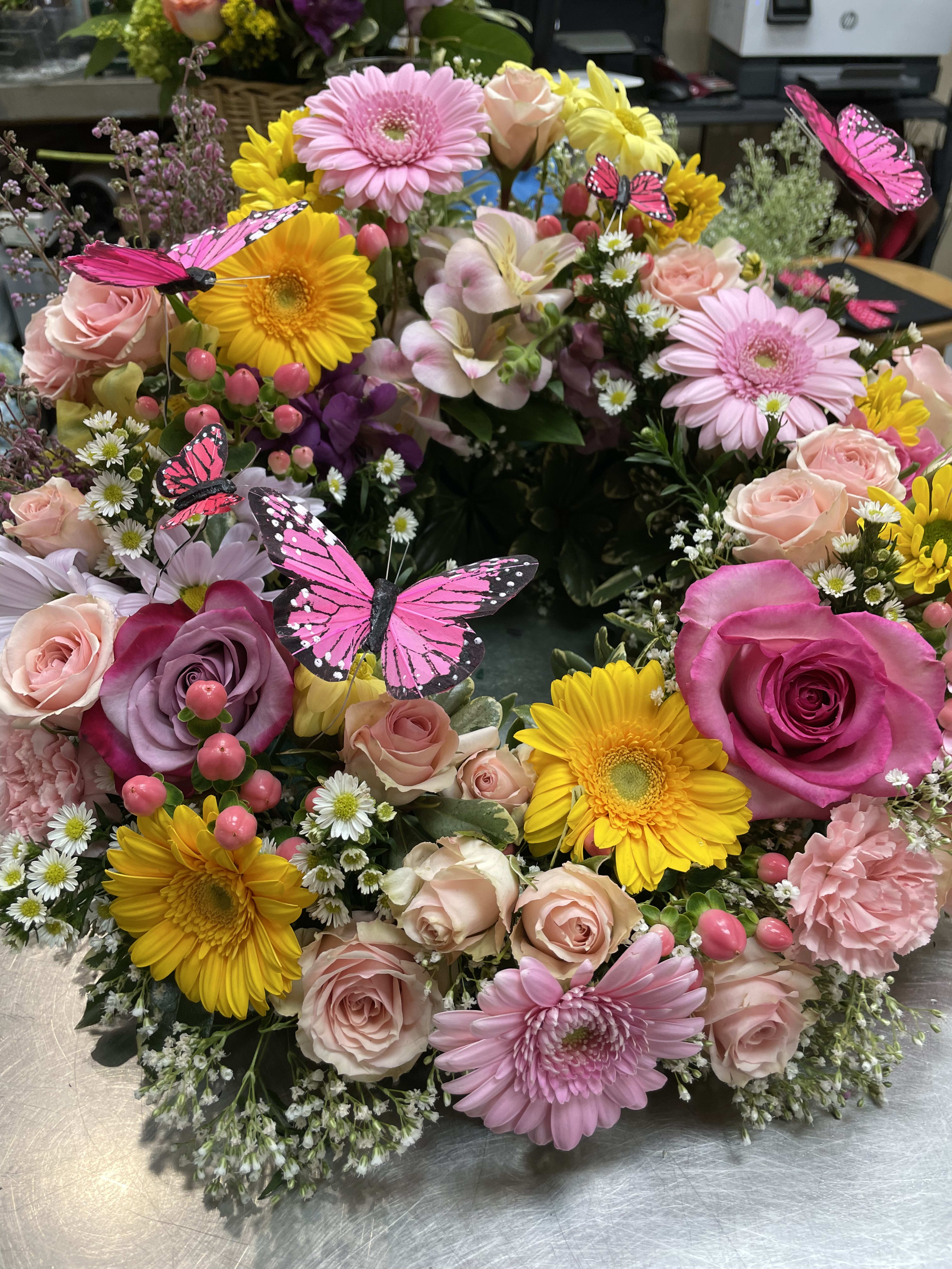 Cremation design with Color. - A colorful ring of flowers to surround your loved one’s  Ashes. We design to the size you need. We like to add butterflies, you can specify if you want them.