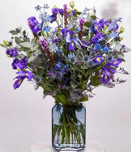 Out of the Blue Bouquet - f you're looking for something to lift the spirits, our Out of the Blue bouquet can add some brightness and help someone feel serene like a calm sea. It’s said that a random act of kindness is the perfect way to beat your own blues, so what better way to spread joy than by sending a loved one this dazzling arrangement? With a glowing selection of blues and purples, this bouquet features irises, lisianthus, delphiniums and other blooms to bring some colour to their home.