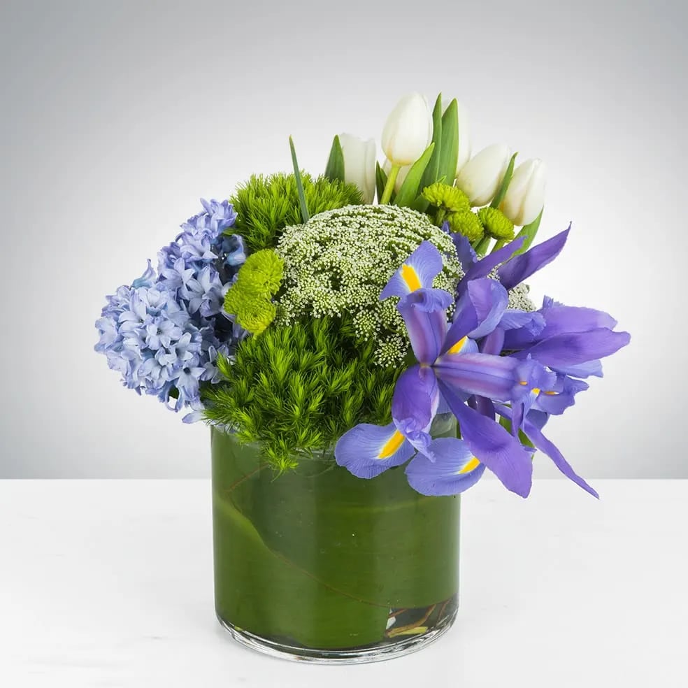 Lush Meadows by BloomNation™ Lush Meadows by BloomNation™ - This arrangement includes green dianthus, blue iris, white tulips, hyacinths, and other seasonal blooms. This is a great spring gift for a birthday, get well, or thank you. APPROXIMATE DIMENSIONS: 10" D x 10" H