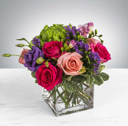 Spring Fling by BloomNation™ - This arrangement includes hot pink roses, pink roses, green hydrangea, freesia, lisianthus, purple statice. Spring Fling by BloomNation™ is a great gift for a birthday, get well, or just because.   APPROXIMATE DIMENSIONS: 12&quot; H X 12&quot; W