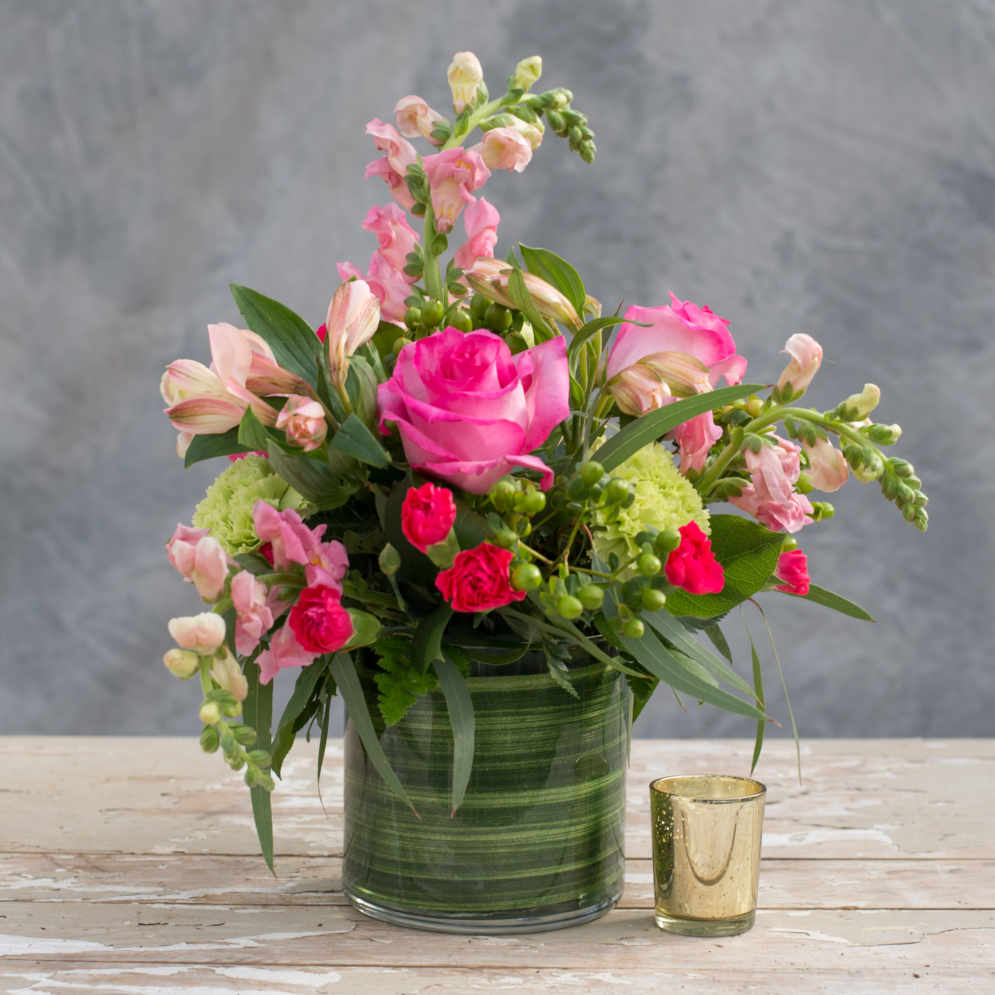 Greenfield - Here's a way to capture the spring and summer even on the gloomiest of winter days.  Choose the Greenfield, a modern clear cube vase with a green ribbon overflowing with various shades of pink and green blooms including roses, carnations, alstroemeria, snapdragons and premium greens.