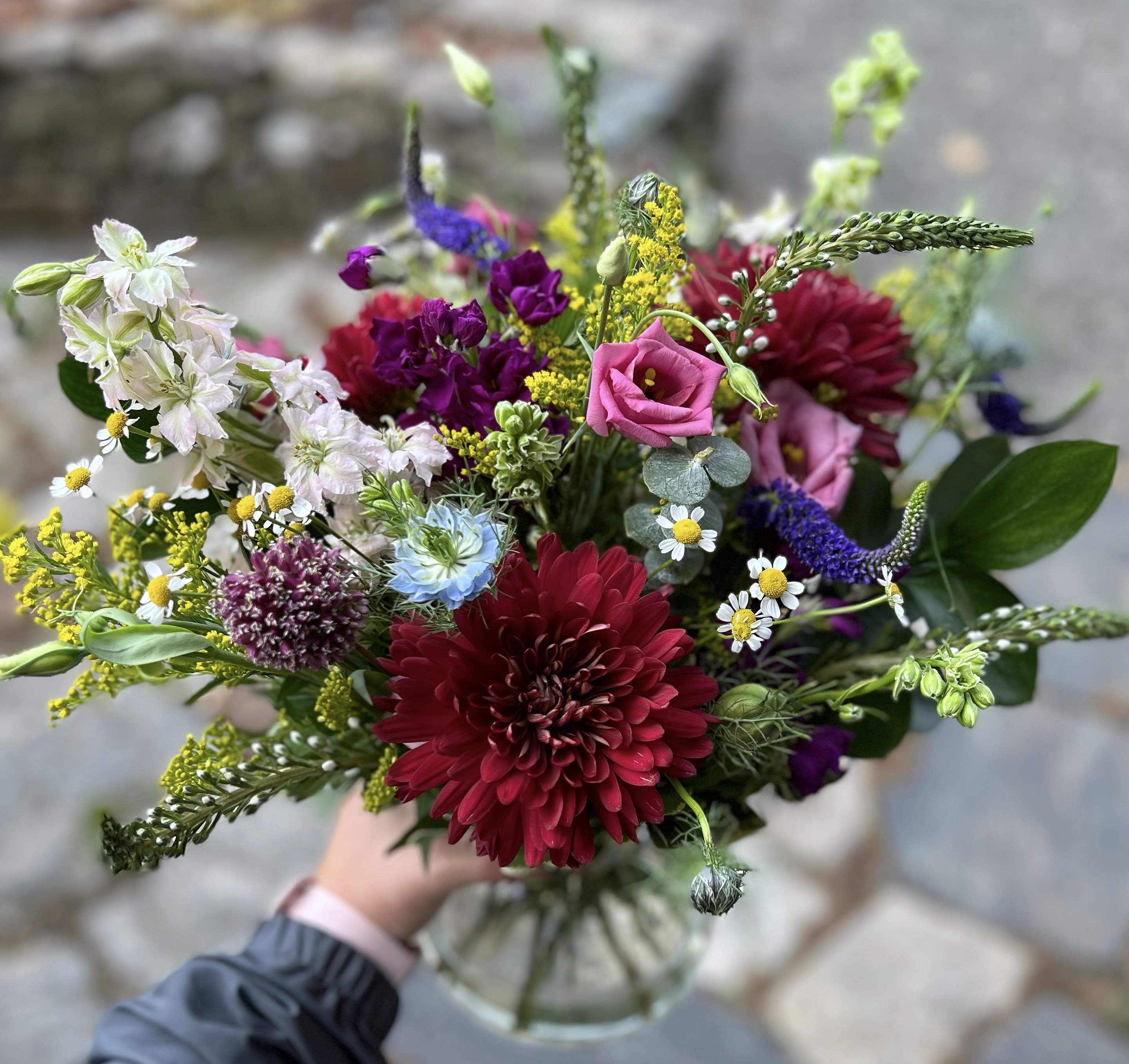 Burgundy Beauty - Lush bouquet is full of color! Mums, stock, lisianthus, Veronica, solidago, eucalyptus to name a few.  Design varies upon availability and sizing. Premium product is shown. The actual product may differ slightly to the photo but will match its size and theme.