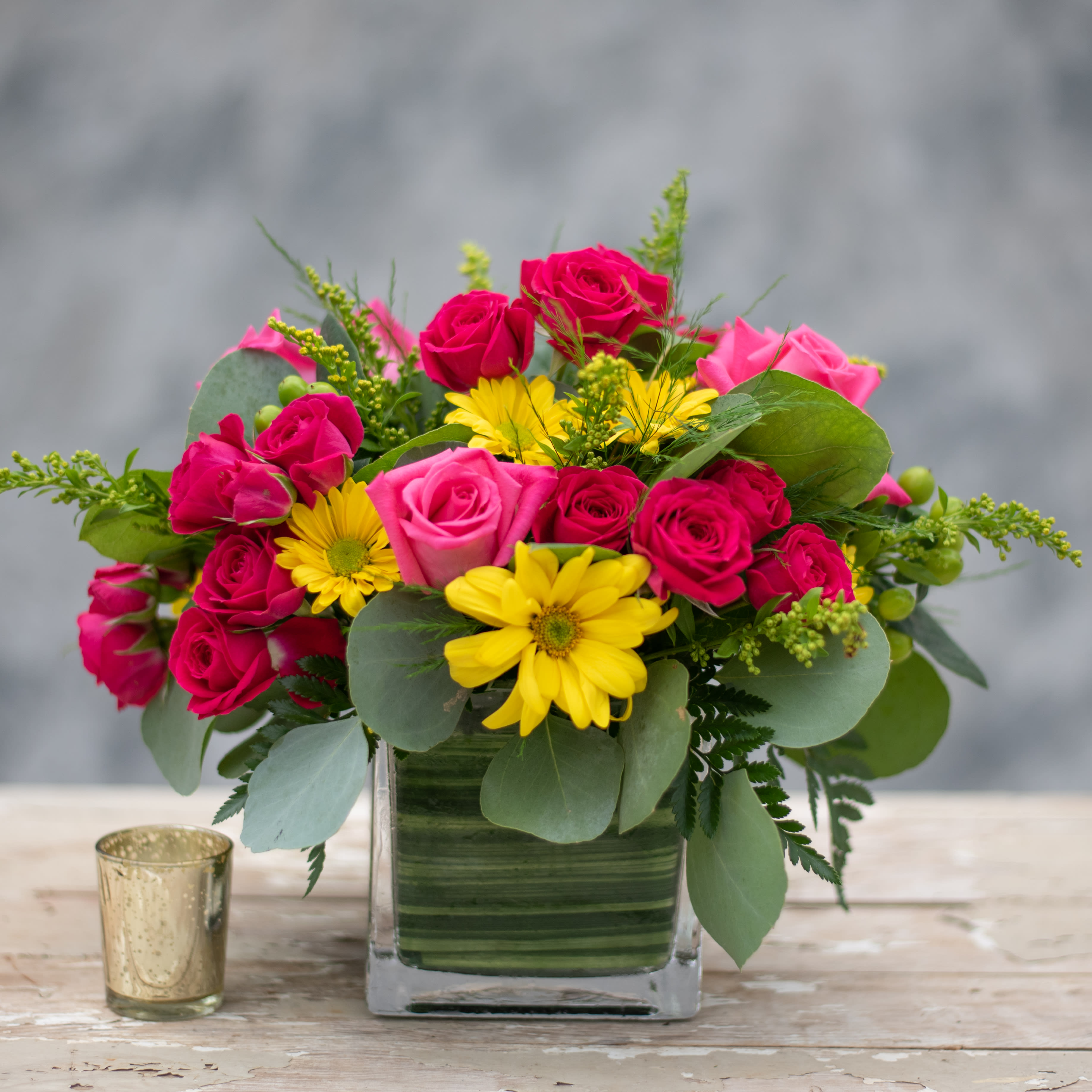 Roseberry - An abundance of pink roses and yellow daisies overflowing a 5' glass cube accented with green hypericum berries and salidago.  Perfect for a coffee table or end table and a perfect hostess gift!