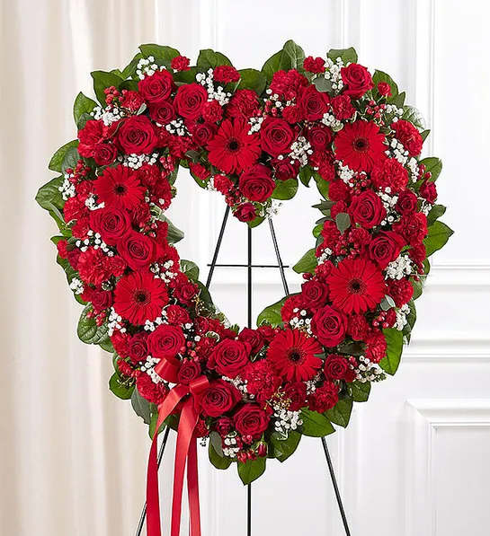 Remember Forever Floral Heart Tribute - Red - For the Service - The love for someone who has passed away lives on forever in the hearts of those left behind. This sentiment is best captured with our standing, open heart-shaped red floral arrangement. Handcrafted by our caring florists with an assortment of radiant red blooms, it is a magnificent tribute fitting for the funeral services.  All-red open heart-shaped arrangement of roses, spray roses, Gerbera daisies, carnations, mini carnations, hypericum; accented with baby’s breath and soft, lush greenery. Arrangement is designed on an easel and accented with satin ribbon. Measures approximately 26&quot;H x 28&quot;W without easel. Appropriate for the funeral home. Our florists use only the freshest flowers available, so colors and varieties may vary.