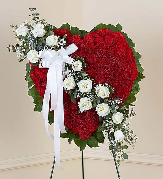 Remember Forever Floral Heart Tribute - Red with White Roses - Honor a loved one with a special tribute. Our heart-shaped standing arrangement of fresh red carnations, accented by a cascading sash of white roses adorned with a white satin ribbon, will help you elegantly express your sincere devotion and sympathy.  Our florists hand-design each arrangement, so colors and varieties may vary due to local availability. Arrangement of red carnations, white roses, gypsophila, spiral and seeded eucalyptus, salal and variegated pittosporum; accented with a white satin ribbon. Arrangement measures approximately 24&quot;H x 34&quot;L without easel. Appropriate to send to the funeral service.