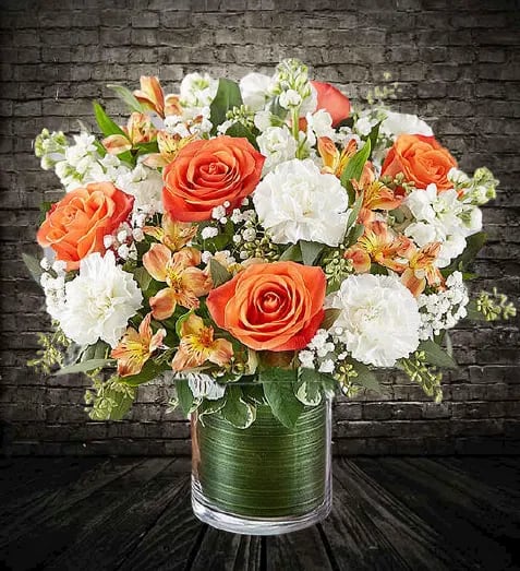 Sweet paradise  - Gathered inside a clear cylinder vase, the mix of vibrant orange and creamy white blooms makes special milestones and everyday moments even more memorable. •All-around arrangement with orange roses and Peruvian lilies (alstroemeria), white carnations and stock; accented with baby’s breath and assorted greenery •Artistically designed a clear glass cylinder vase