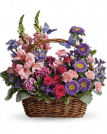 Country Basket Blooms - Talk about a bountiful basket! This wicker basket is overflowing with beauty and blossoms. It's no wonder two pretty butterflies have made this basket their home. Hot pink spray roses, light pink alstroemeria, snapdragons and miniature carnations, dark pink Sweet William, purple matsumoto asters, large monte cassino asters, statice and pittosporum fill a pretty picnic-like basket. You've got this gift handled! One Sided 16&quot;Wx17&quot;H