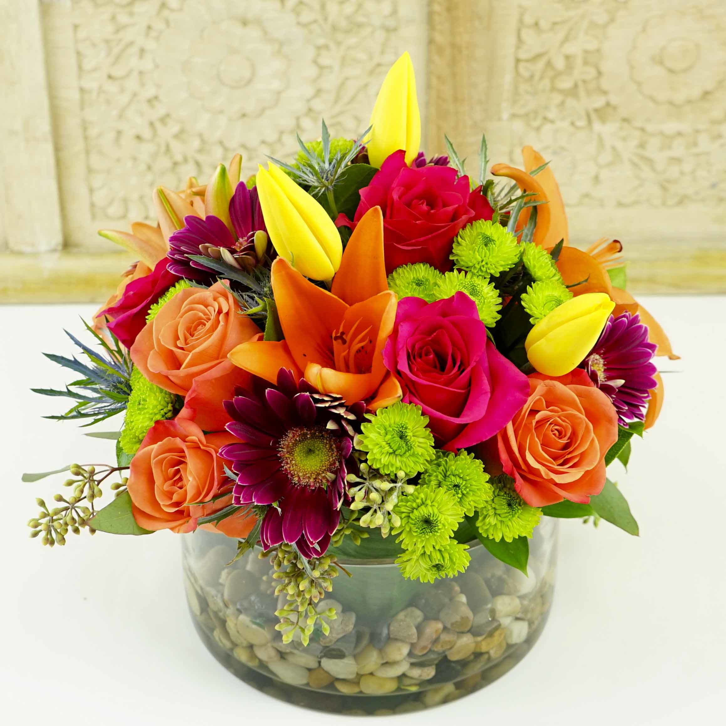 A COLORFUL SUMMER - A colorful mixture of seasonal flowers such as Tulips, Asiatic Lilies &amp; Roses, seasonal fillers design in a glass cylinder lined with an artificial leave. Approx. size: 10&quot; tall by 12 wide VCY0804
