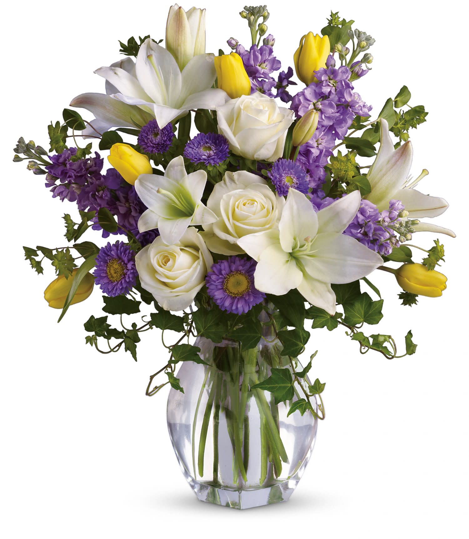 Spring Waltz - Serene crÃ¨me roses, yellow tulips, white asiatic lilies, lavender stock and matsumoto asters are perfectly arranged with spring's freshest greenery and delivered in a lovely clear glass vase. Send it and you'll definitely waltz right in to someone's good graces! Approximately 17 1/2&quot; W x 20&quot; H  T141-1A