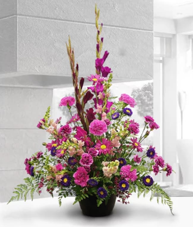 Fuchsia and Purple A-Line - This traditional A-Line style arrangement is a favorite for many occasions.  Substitutions of equal or greater value may be made depending on season and availability of product or container.   Photo Represents Deluxe Pricing.  CH5532