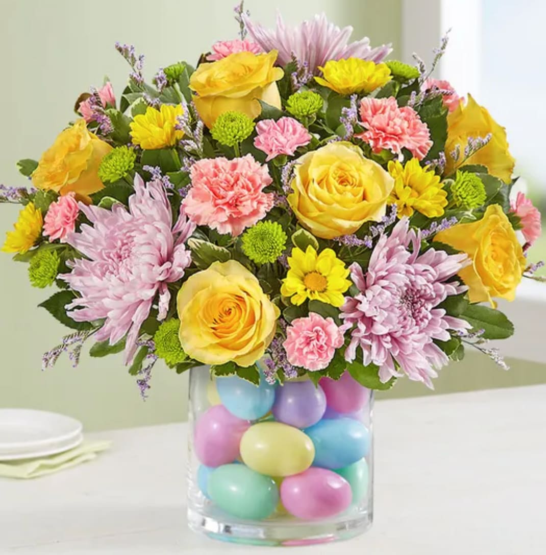 Easter Egg-Stravaganza™ - Our pastel bouquet brings fresh-picked spring beauty—and plenty of fun—into every home at Easter. Softly-colored blooms are gathered in a clear glass cylinder vase filled with colorful eggs for a uniquely playful touch. Surprising family &amp; friends or decorating your own table, this gift’s sure to make the holiday celebration even more special.