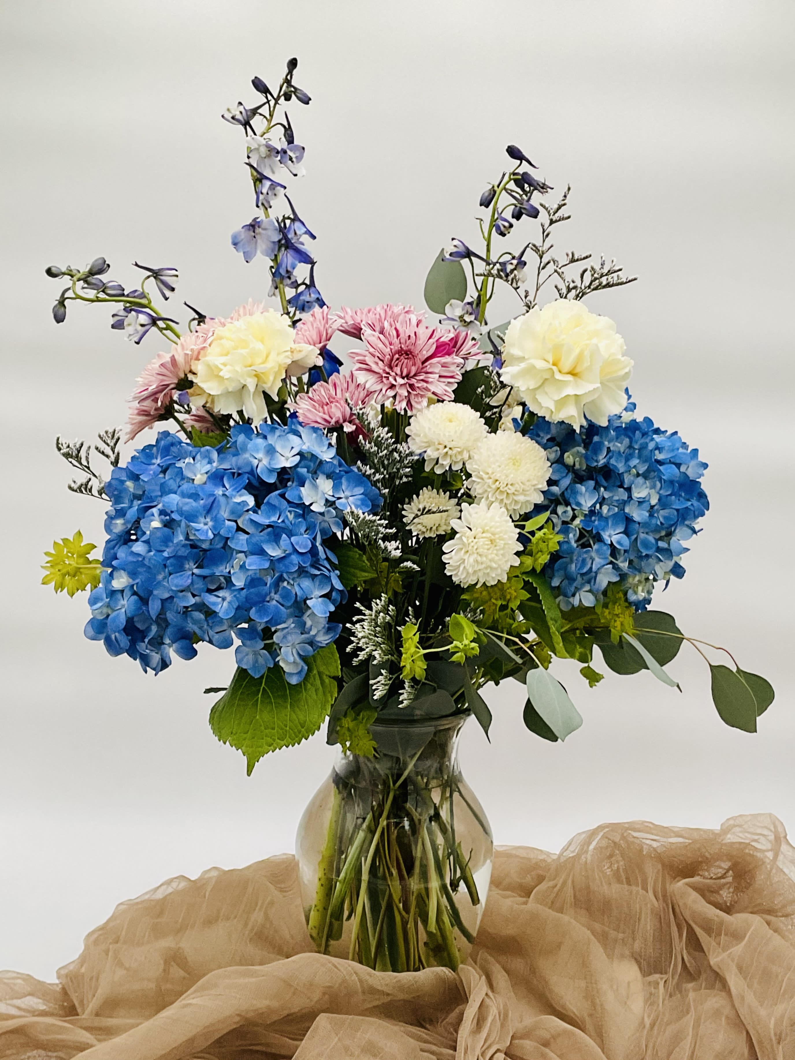 Ocean Breeze - Inspire dreams by the shore with our Ocean Breeze arrangement.  This bouquet features hydrangeas, carnations, crysanthemums, and delphinium; accented with greenery.