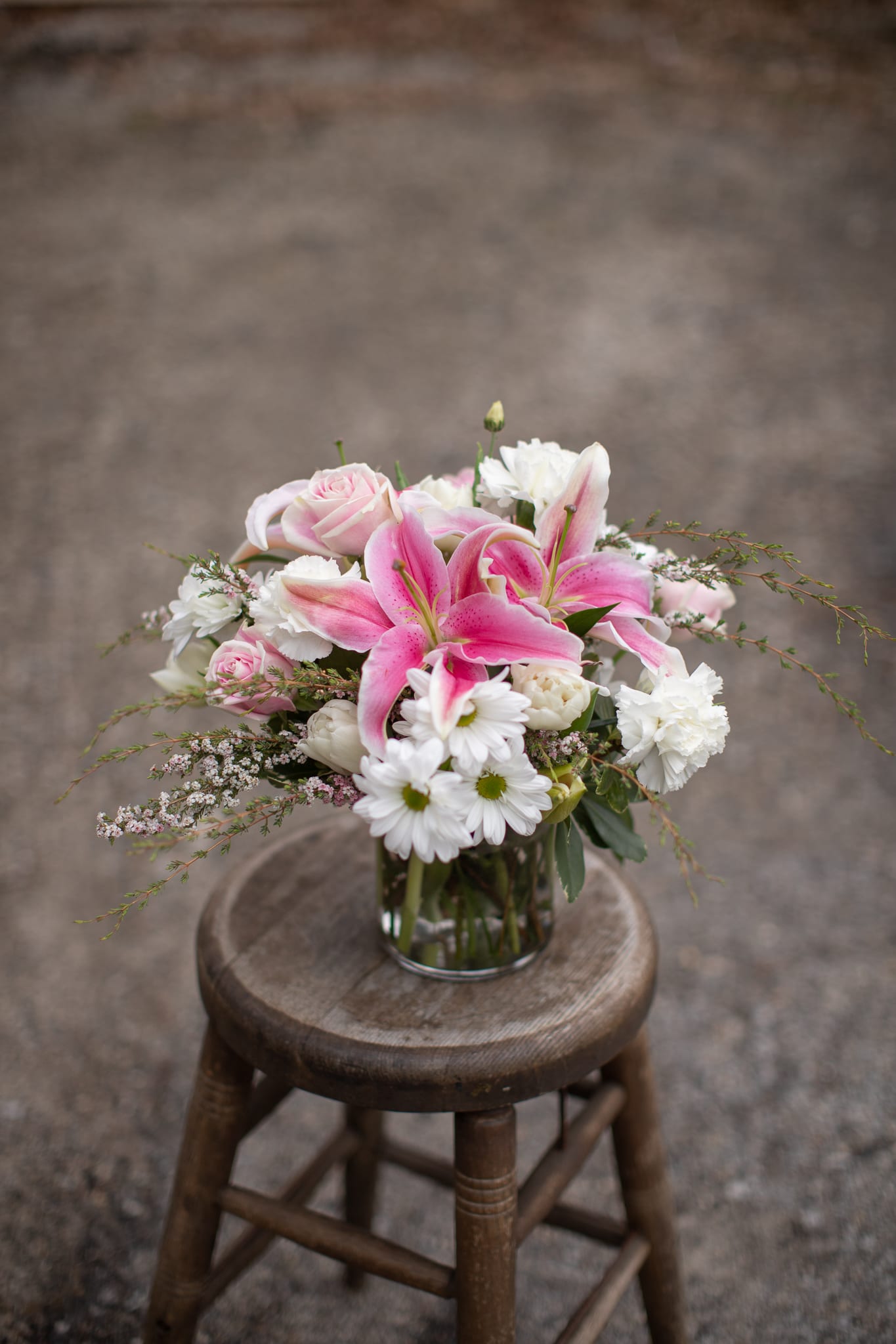 Pretty in Pink Bouquet - A beautiful pink bouquet perfect for any occasion. A pink lily is the focal point of this cylinder or cube vase arrangement. Other flowers surrounding it may vary due to seasonality. Whites and pinks will surround the focal flower. This arrangement is perfect to send to welcome a new baby girl or just a little something special for those friends who are passionate about the color pink.
