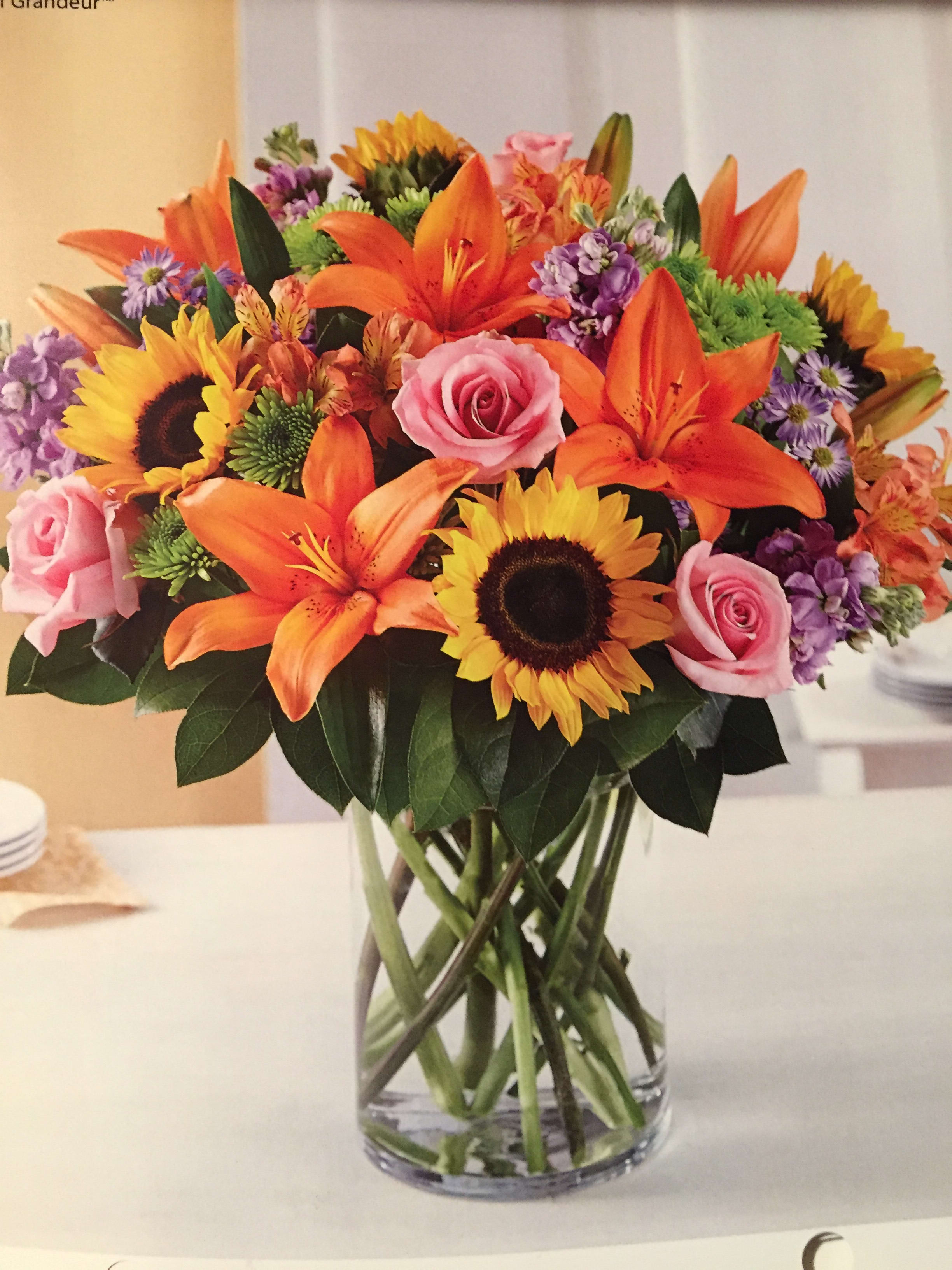 Lilies and sunflowers delight  Not available for Valentine's Day - Orange lilies, carnations, alstroemeria, green button mums and hot pink roses with greens in clear vaseand orange bow.