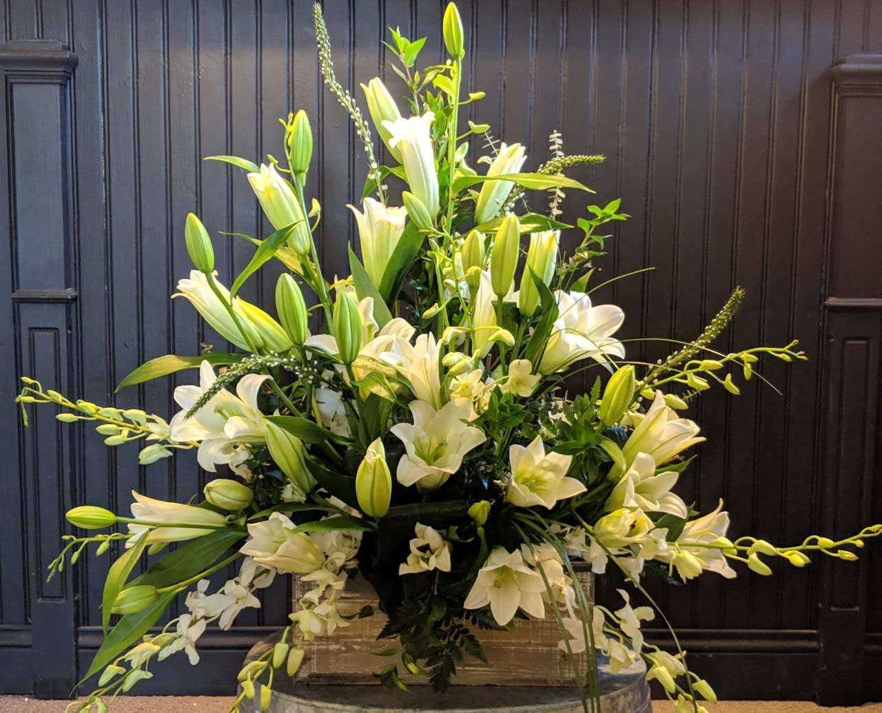 Simply Serene - This tastefully simple arrangement is designed with all white lilies, orchids, and mixed greens in a unique boxed base.  