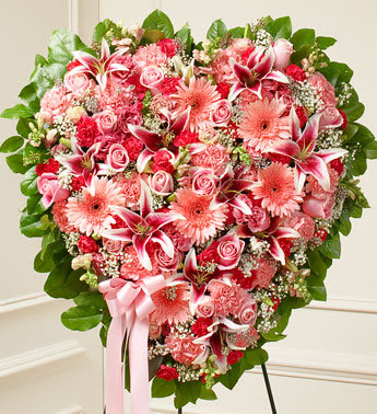 Pink Mixed Flower Heart -    This solid heart standing spray is a beautiful symbol of your sympathy and support. Pink flowers such as roses, stargazer lilies, Gerbera daisies, carnations and more Solid heart with oasis in mache, tied to the wire easel with satin ribbon Sent directly to the funeral home by family and friends Our florists use only the freshest flowers available so components may vary Measures approximately 26&quot;H x 26&quot;L