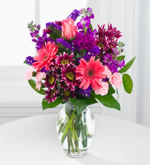 Garden Beauty Bouquet - Intended to capture their every attention the Garden Beauty Bouquet pops with color and a soft fragrance to send your sweetest wishes to your special recipient! Picked fresh from the farm this bouquet exhibits the winning color combination of pink and purple bringing together hot pink gerbera daisies pink roses purple gilly flower purple chrysanthemums purple mini carnations pink mini carnations purple statice and lush greens to create an exceptional gift. Presented with a classic clear glass vase this fresh bouquet is set to make that perfect impression when sent to celebrate a birthday or express your get well or thank you sentiments. 9 stems.