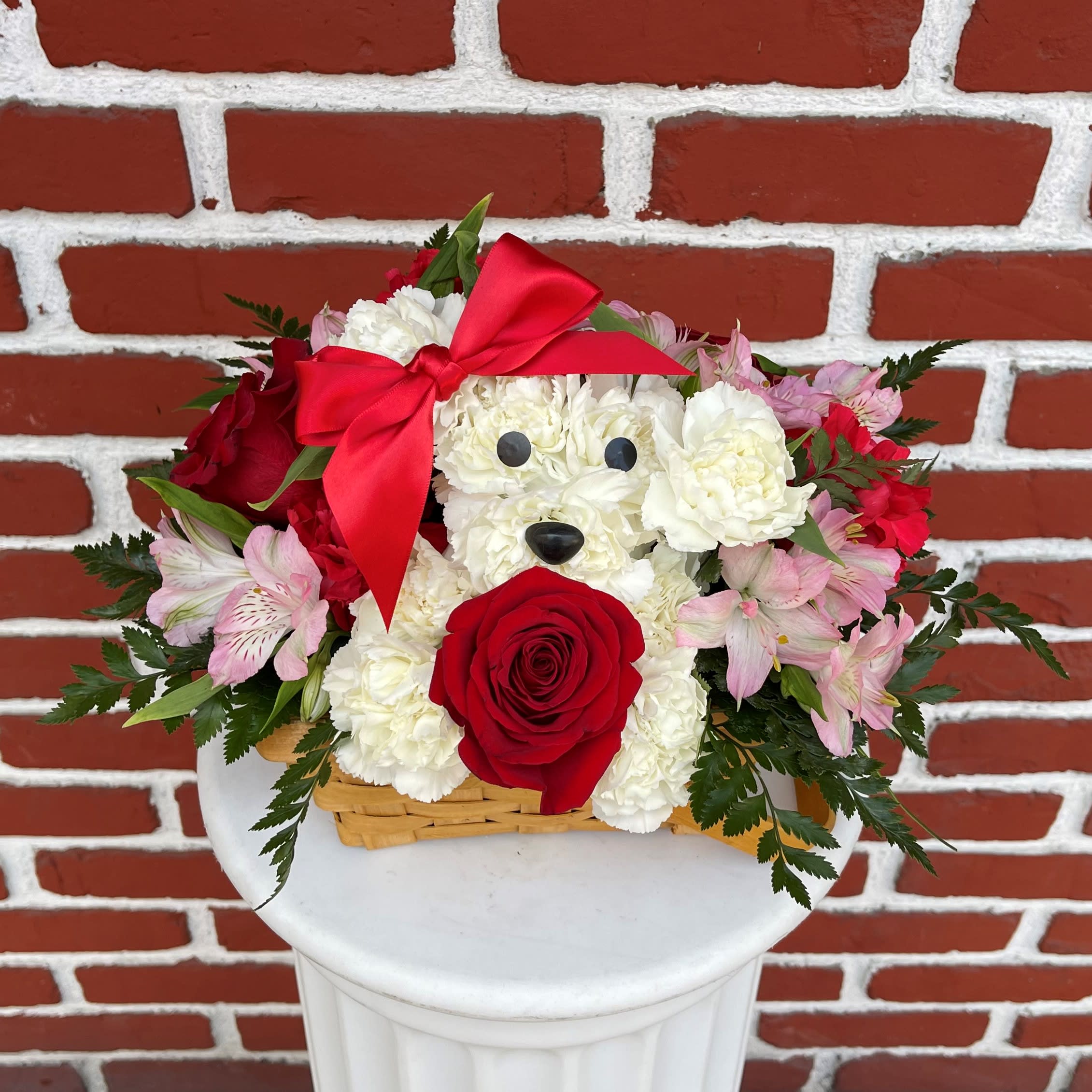 Puppy Love Puppy Love - Puppy Love! Perfect for sparking a romance or celebrating a special relationship. Includes white carnations, red roses and mini carnations, pink alstroemeria, and greenery. Artistically crafted in the shape of a dog, with eyes, nose, and red satin ribbon in a basket. Each arrangement is hand-designed by our florists, so varieties and colors may vary due to availability.