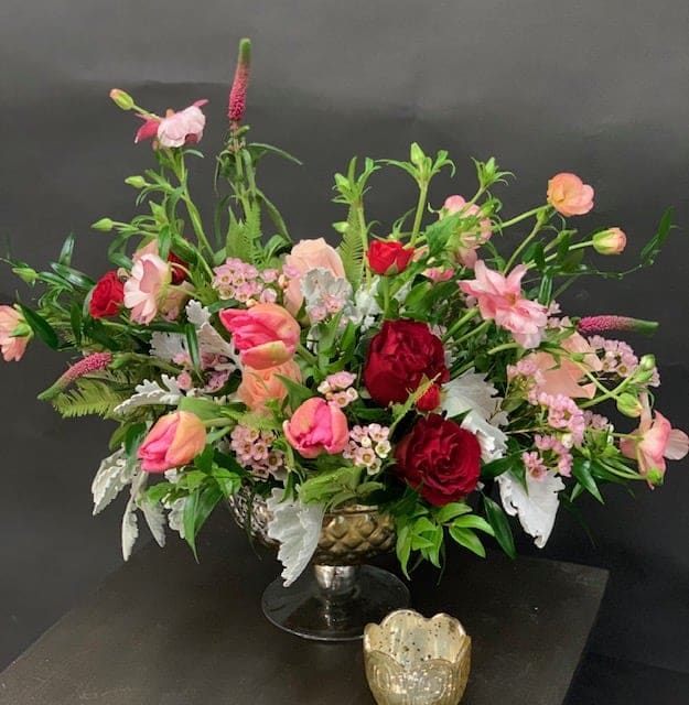 Moon Struck - An organic floral arrangement filled with mixed blooms in hues of pinks, reds and greens arranged in a glass mercury urn. 