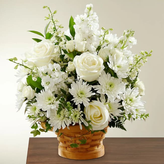 Heartfelt Condolences Arrangement - Let this exquisite composition of beautiful white blossoms deliver your sympathy and comfort loved ones grieving a loss. The elegance of this arrangement and its warm, homey basket base makes it an appropriate addition to any wake, funeral or graveside service, or to send to the home of family or friends. Handcrafted by our expert designers of individually selected white roses, stock, cushion pompons and larkspur set among complementary greens for a memorable bouquet that evokes a tranquil sense of heavenly hope.  Please Note: The bouquet pictured reflects our original design for this product. While we always try to follow the color palette, we may replace stems to deliver the freshest bouquet possible, and we may sometimes need to use a different basket. DETAILS 22&quot;h x 21&quot;w BLOOM DETAILS Larkspur Rose