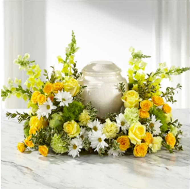 Graceful Love Cremation Adornment Graceful Love Cremation Adornment - Celebrate the life of a loved one with the Graceful Love Cremation Adornment. This gloriously golden sympathy arrangement includes yellow roses, snapgragons, white daisy poms, and carnations. DETAILS Approximately 16"h x 24"w