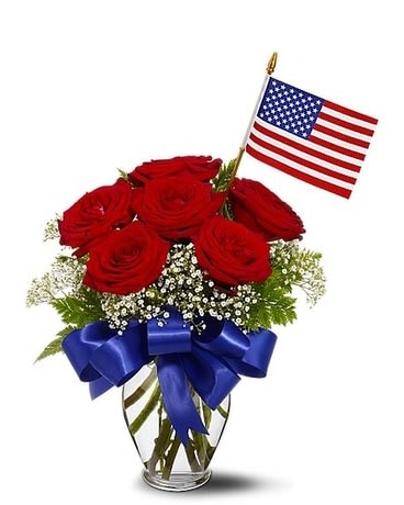 Star Spangled Roses Bouquet - Celebrate the spirit of freedom with six beautiful red roses, nestled in a puff of white gypsophila, and topped off with an American flag! A big, shiny blue bow completes this patriotic bouquet that's perfect for Memorial Day, the 4th of July or any day of the year. Six red roses, accented with Million Star gypsophila and leatherleaf fern â and decorated with a blue ribbon and an American flag â are delivered in a classic glass urn.