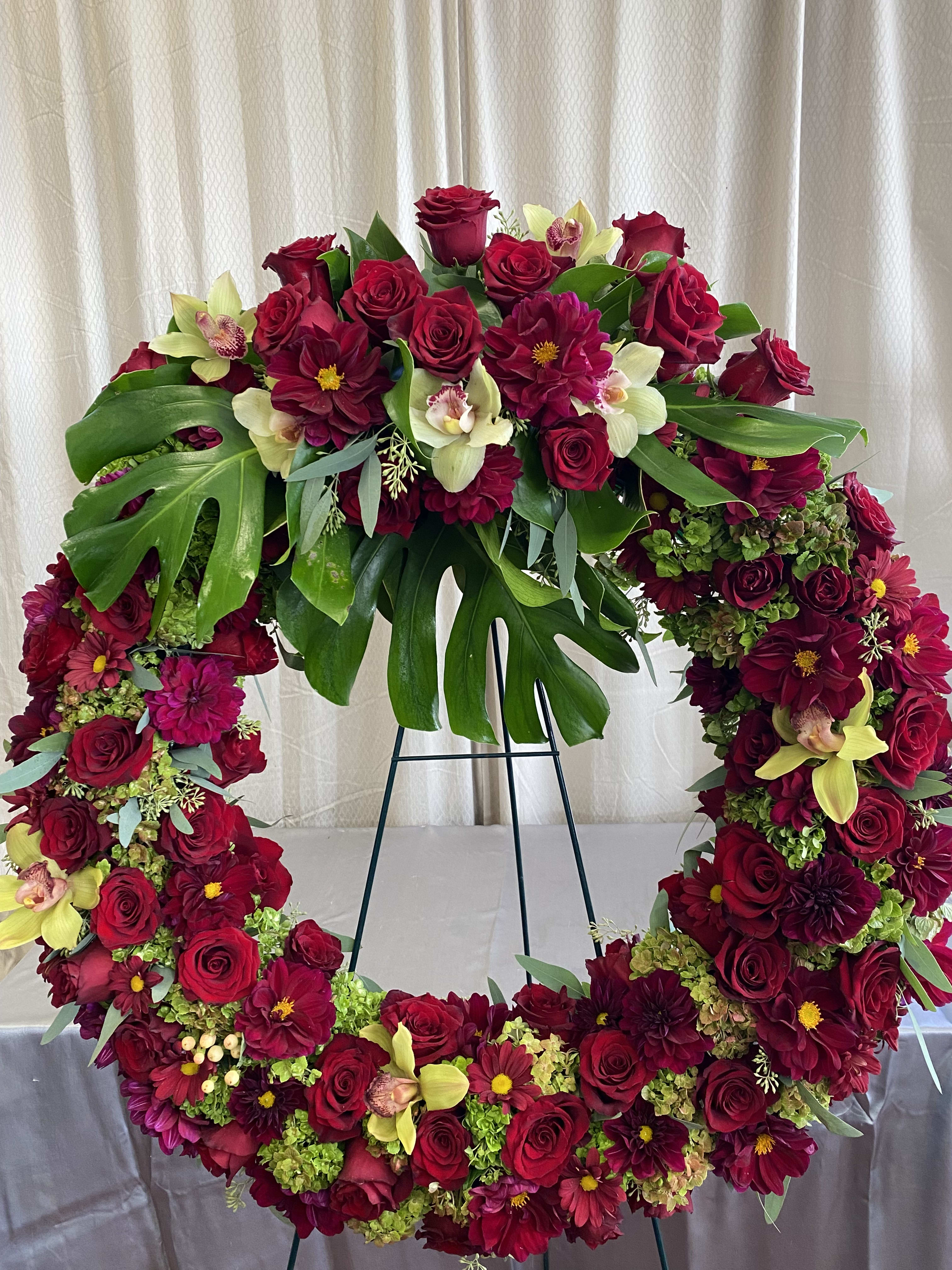 #43 - Red Lovers Wreath #43 - Red Lovers Wreath - This 34-inch red and green wreath is guaranteed to please the eye. The subtle reds of the roses, dahlias, and daises, The delicate greens of the leaves, orchids and hydrangeas. Please Note! Please call ahead of time to guarantee the same type of flowers!