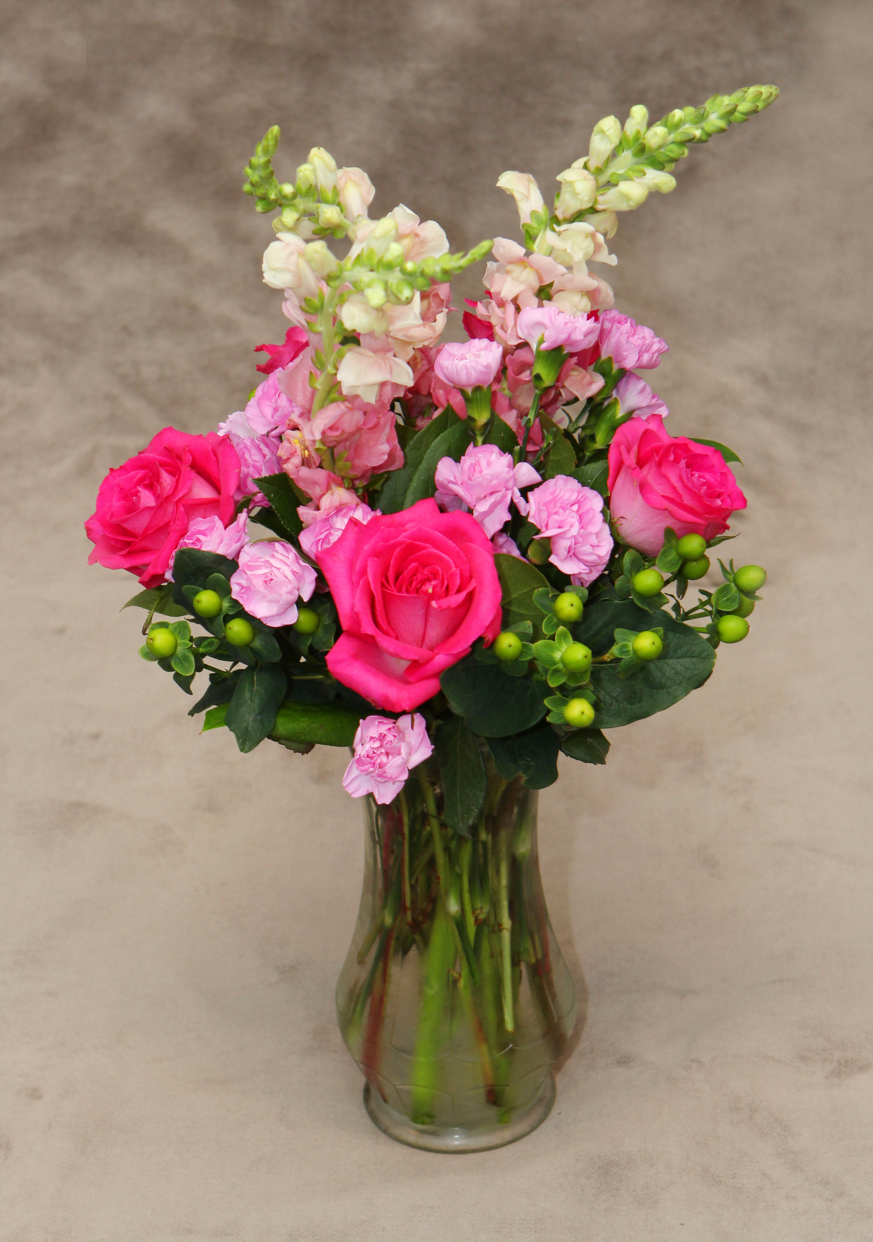 From The Garden - Mixture of snapdragons , mini carnations , green coffee bean , and hot pink roses. Makes this arrangement a delightful assortment of garden flowers. 