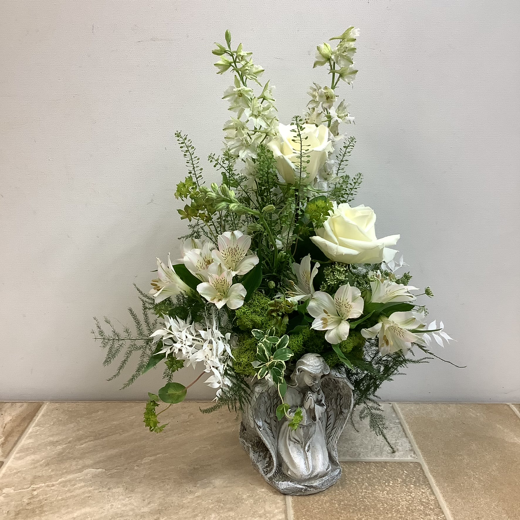 Enduring Beauty - A memorable bouquet designed in a lovely resin angel vase. It’s filled with a collection of all white fresh flowers including roses, alstroemerias and larkspur. It measures 14” wide x 17” tall