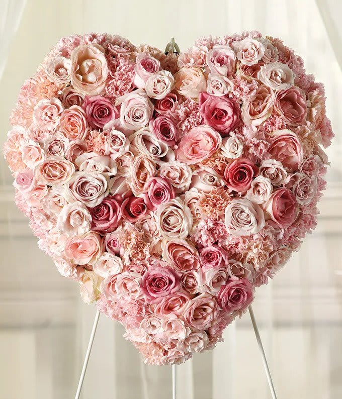 Hearts Rose with Stand - Delicate pink roses and carnations fill this heart shaped arrangement for a graceful expression of sympathy. This arrangement is traditionally sent directly to the funeral home to be displayed on a stand. 