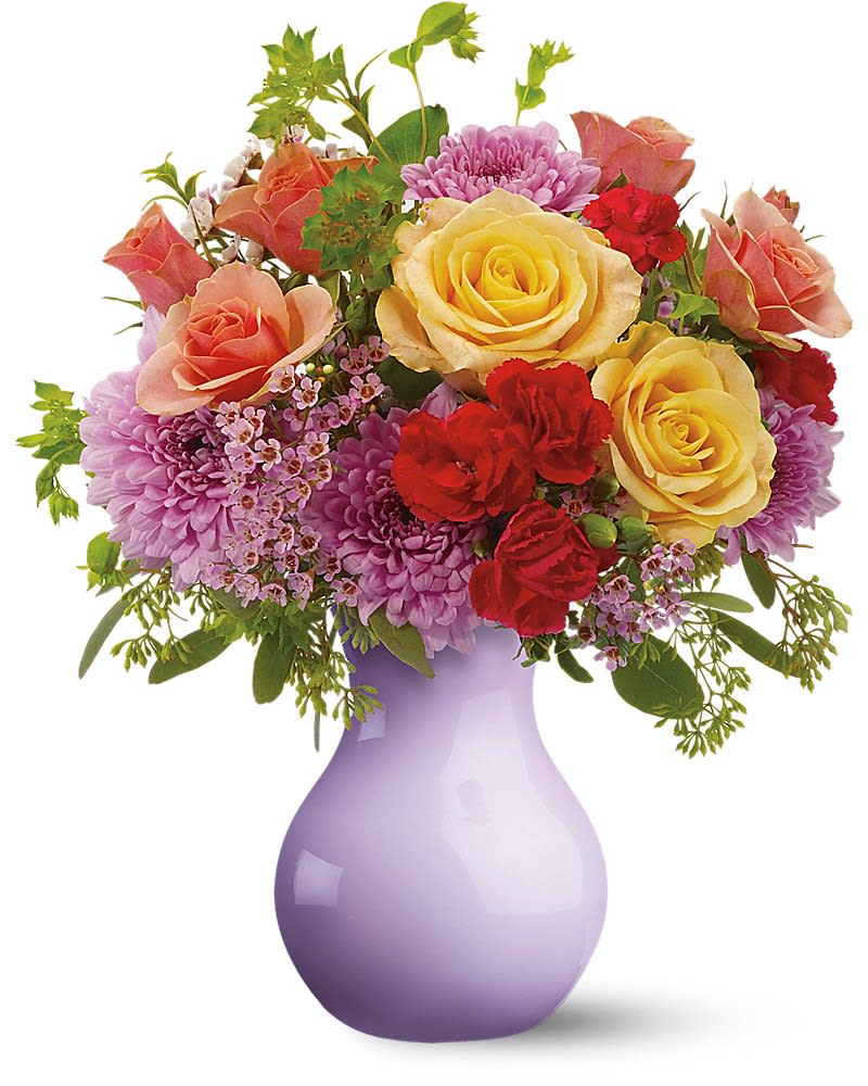 Teleflora's Stratford Gardens - For a gift that's reminiscent of a stroll through the English countryside, send this stunning mix of pink and peach roses mingled with cool lavender chrysanthemums, arranged in a misty lavender vase. It's as charming as a cottage garden. Pink spray roses, waxflower and hot pink miniature carnations, plus peach roses and lavender cushion spray chrysanthemums - accented with bupleurum, seeded eucalyptus and oregonia - are delivered in a lavender sweetheart vase.