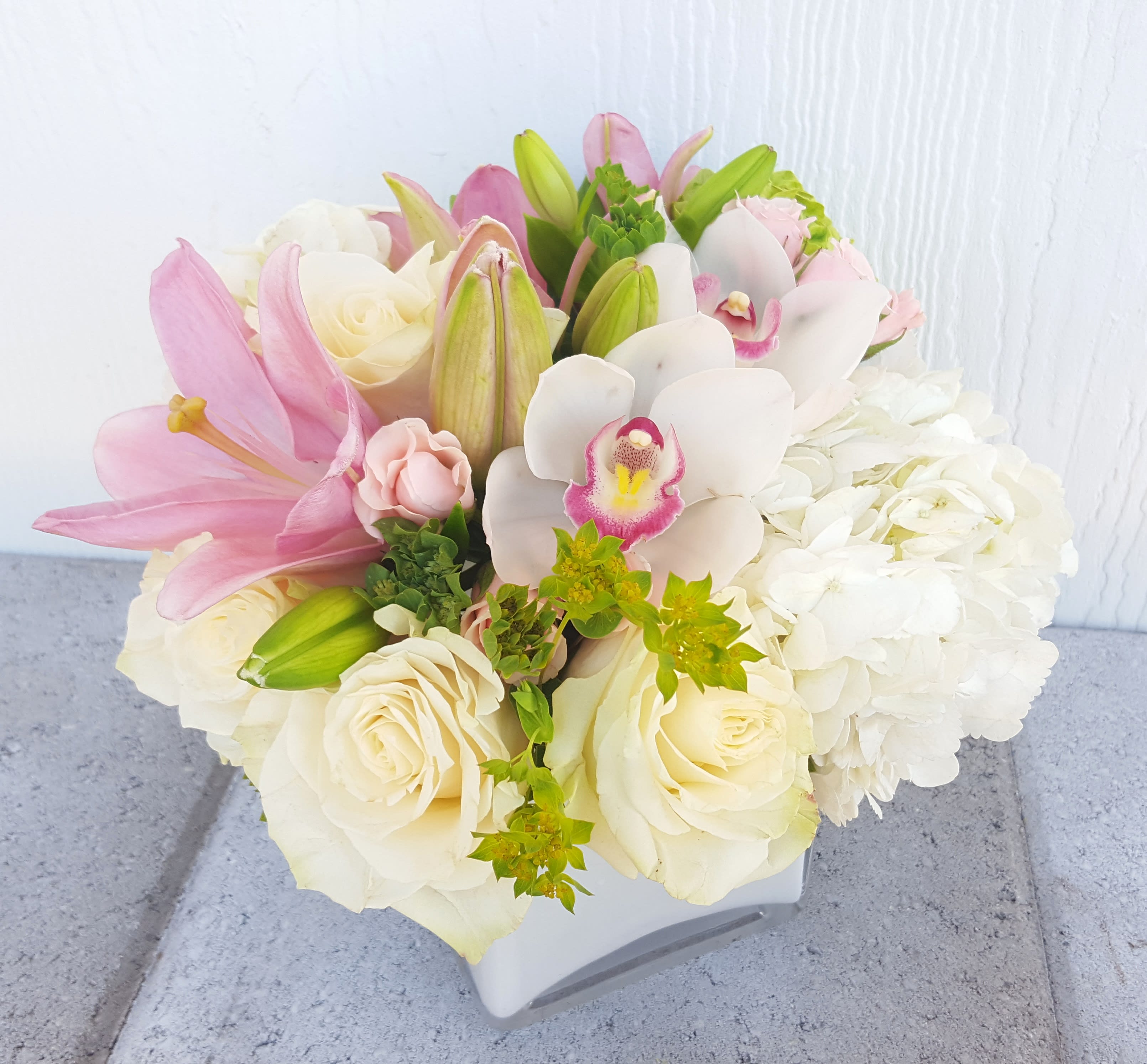 Blushing Beauty - Beautiful blush and white in this arrangement with  roses, hydrangea, orchids and more. Measures approximately 10&quot; wide x 10&quot; high. Comes in a Clear cube 