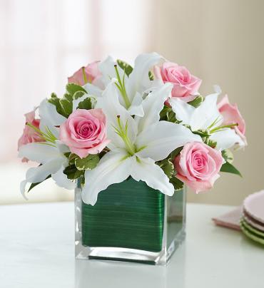 Modern Embrace Rose and Lily Cube Bouquet -  Contemporary elegance meets classic style with this stunning bouquet. Gorgeous fresh pink roses share the stage with showy white lilies, hand-designed and arranged by our select florists in a compact style. Then, this dynamic duo is gathered in a chic cube vase lined with exotic ti leaf ribbon.    Item # 91116 