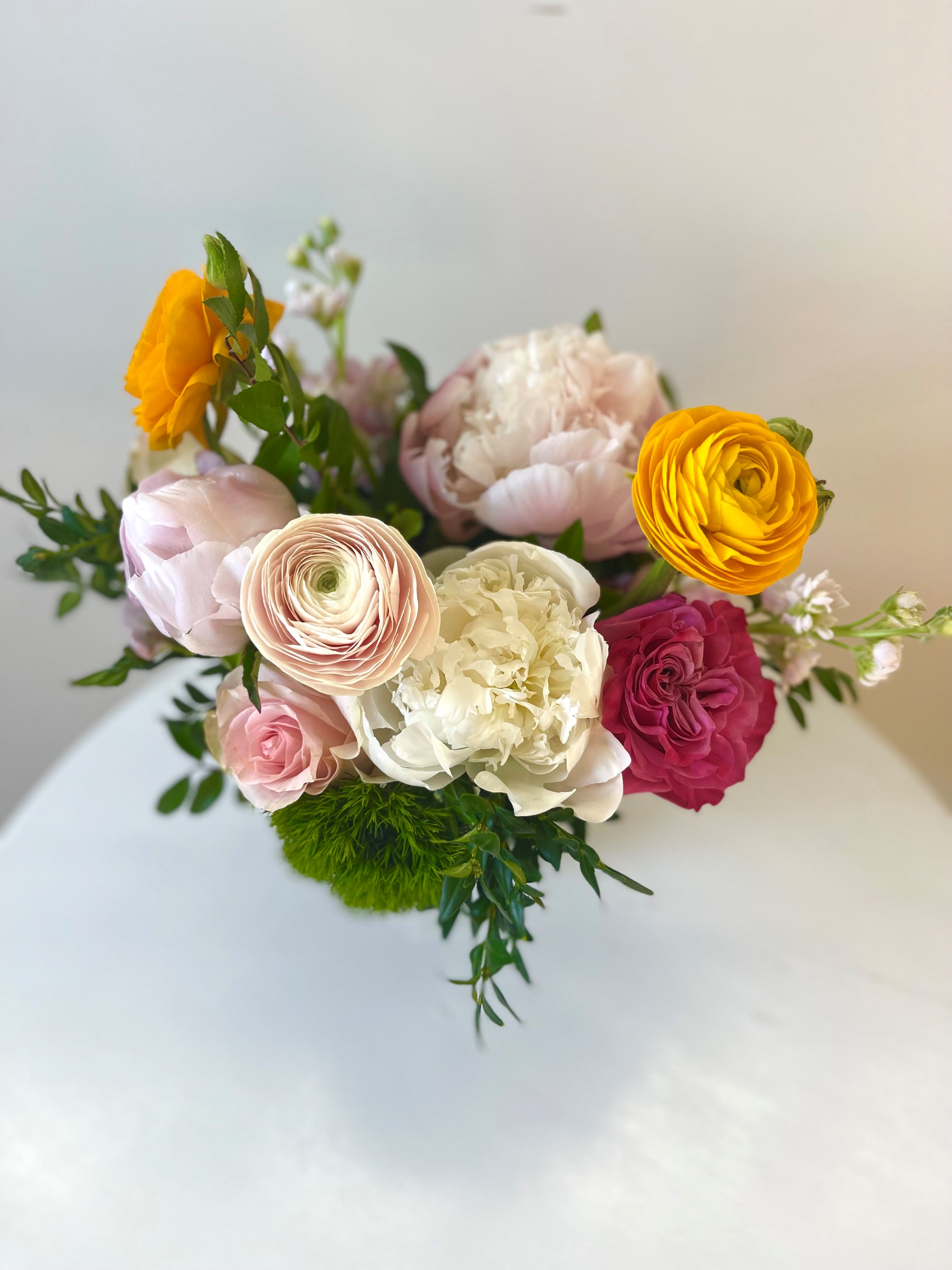 Pops of Color - This perfect fishbowl filled with ranunculus, peonies and roses is a great pop of color that is sure to make them smile.