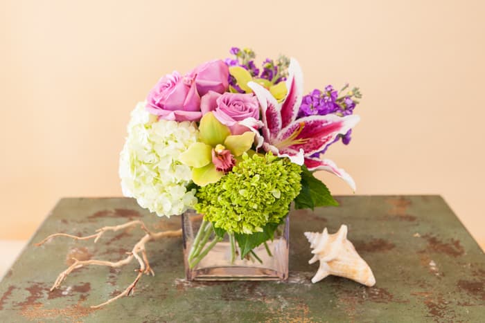 Sweet Embrace - A stunning, pastel compact arrangement of hydrangea, roses, lilies, orchids and other complementary flowers arranged in a clear glass cube. Modern and soothing, this design is sure to please.  Flower colors may vary week to week, please call if this is a concern.