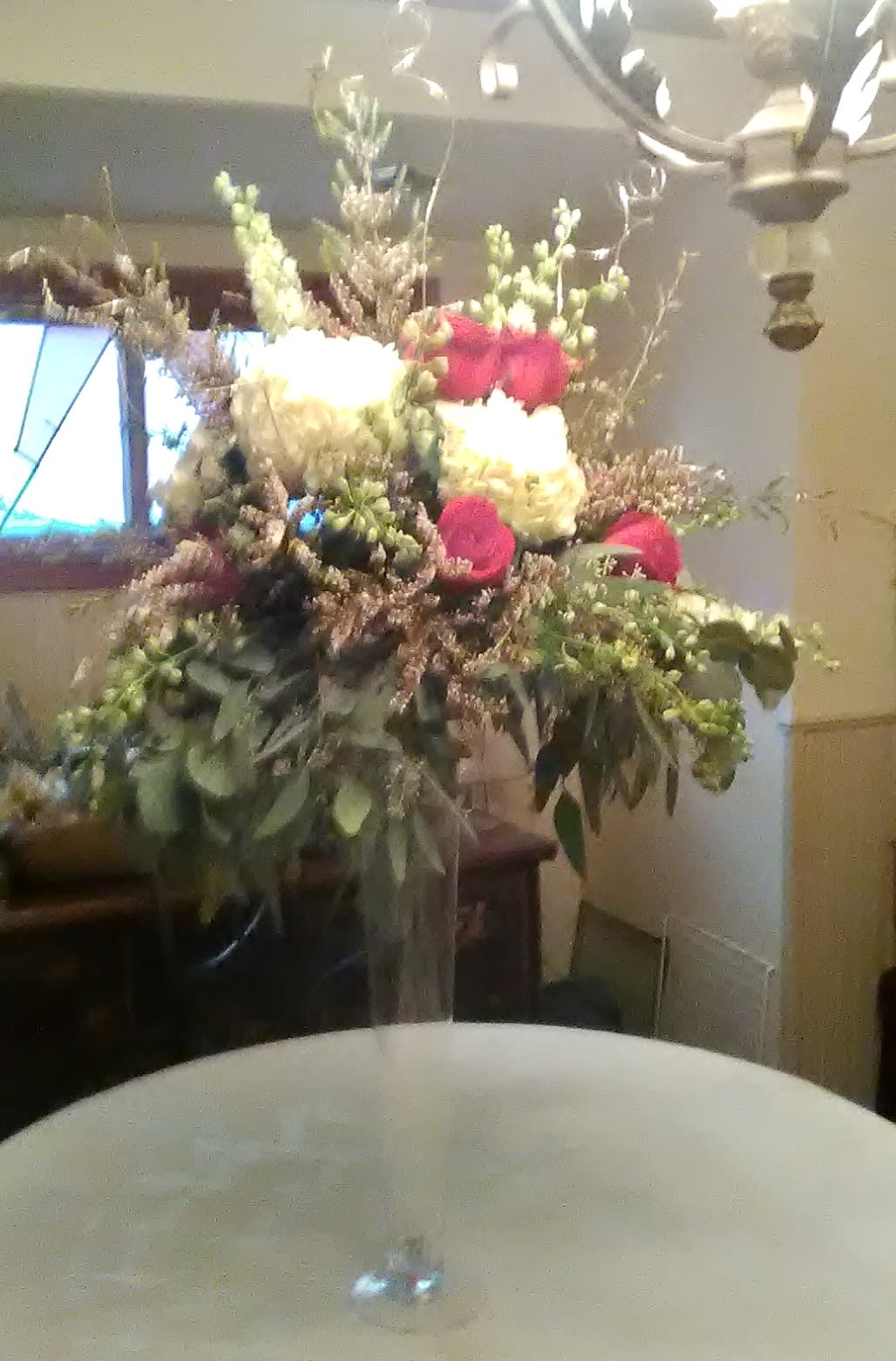 Tall Centerpiece with hydrangea, roses and fillers - Tall, elegant centerpiece in a tall glass vase overflowing with roses, greenery, hydrangeas and fillers.