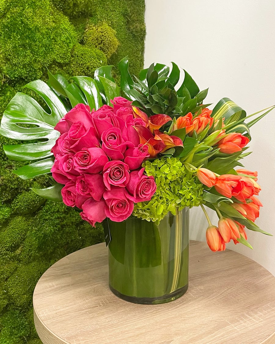 Floral Crush - Hot pink roses and orange tulips accented with tropical leaves. Overall arrangements height is about 18&quot;