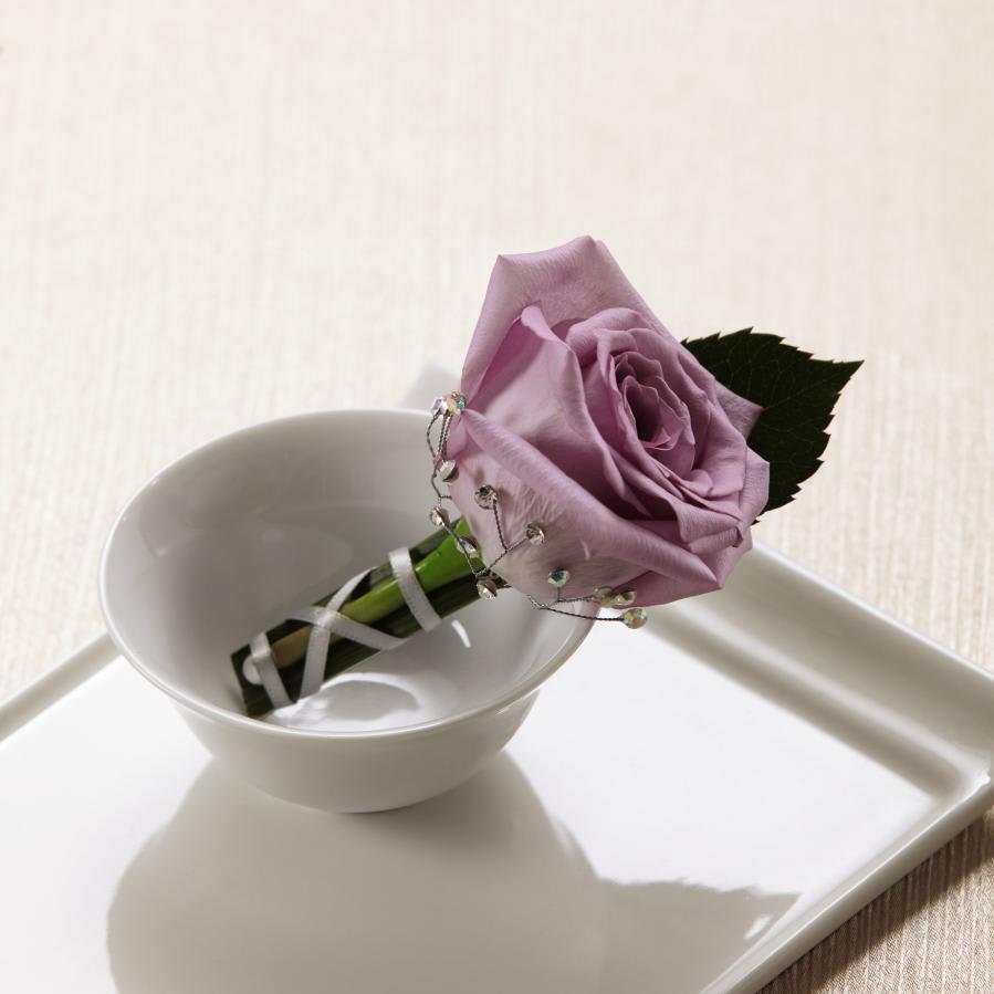 FTD New Love Boutonniere - The FTDÂ® New Loveâ¢ Boutonniere is the perfect way to complete the look  of your wedding party. A single lavender rose is accented with a lily  grass blade, rhinestone spray pics, pixie pearl pins and a silver gray  French taffeta ribbon to create a sophisticated and distinguished look.  Approx. 3âH x 2âW.  