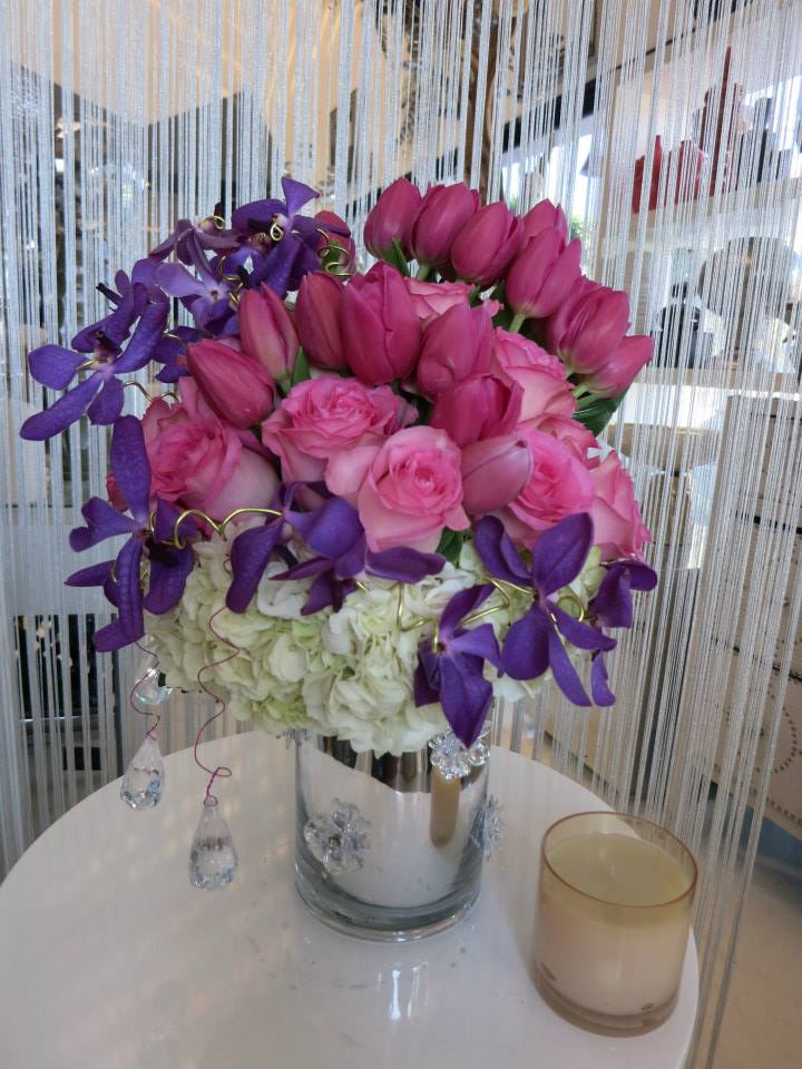 The Princess Arrangement - A bright arrangement perfect for any princess! This lush combination of roses, tulips, and orchids sits in a silver flower embossed reflective vase with dangling decorative crystals sparkling.