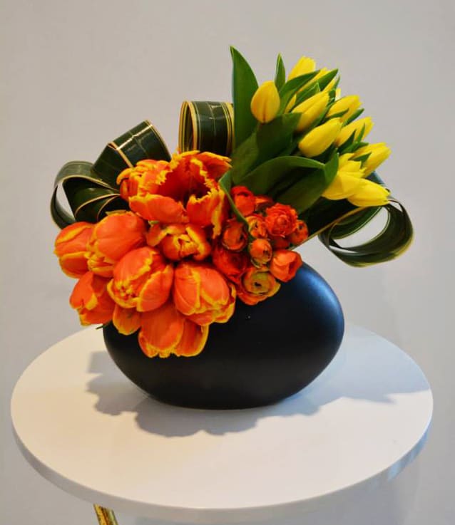 Citrus Sweet Citrus Sweet - A modern arrangement with bold yellow and orange tulips, and deep orange ranunculus in a matte black ceramic vase. *vase subject to availability