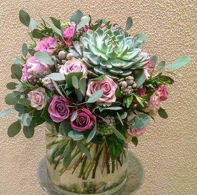 Beyond Beauty  - Designed in a cylinder vase, purple roses, hyacinths, fillers and a variety of greens with a live succulent that can be replanted, these beautiful flowers are to impress.