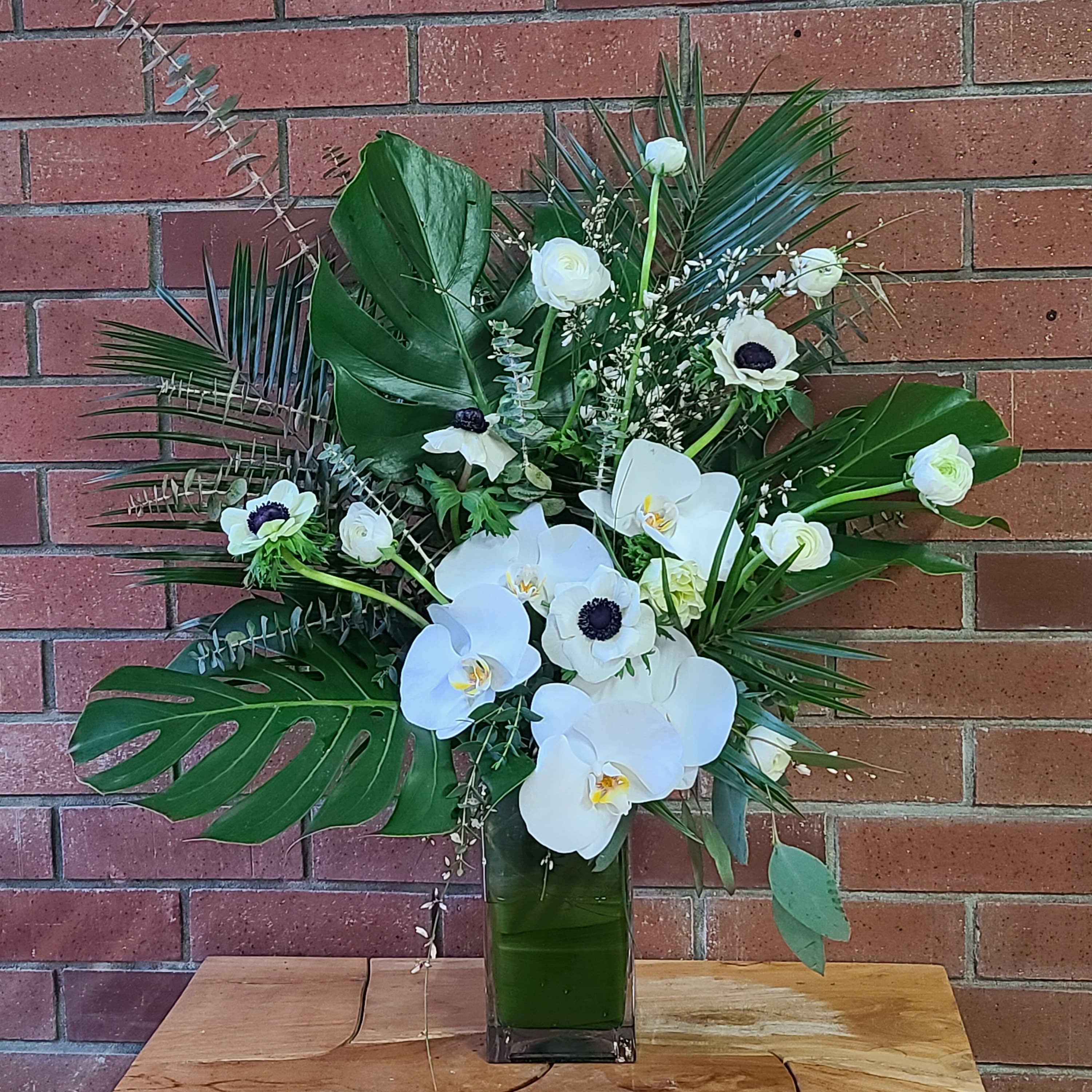 Grand Palm - A luxurious modern display of larg palm leaves, monstera leaves, white orchids and other white tropical florials to make up a magical gift for anyones home or service.