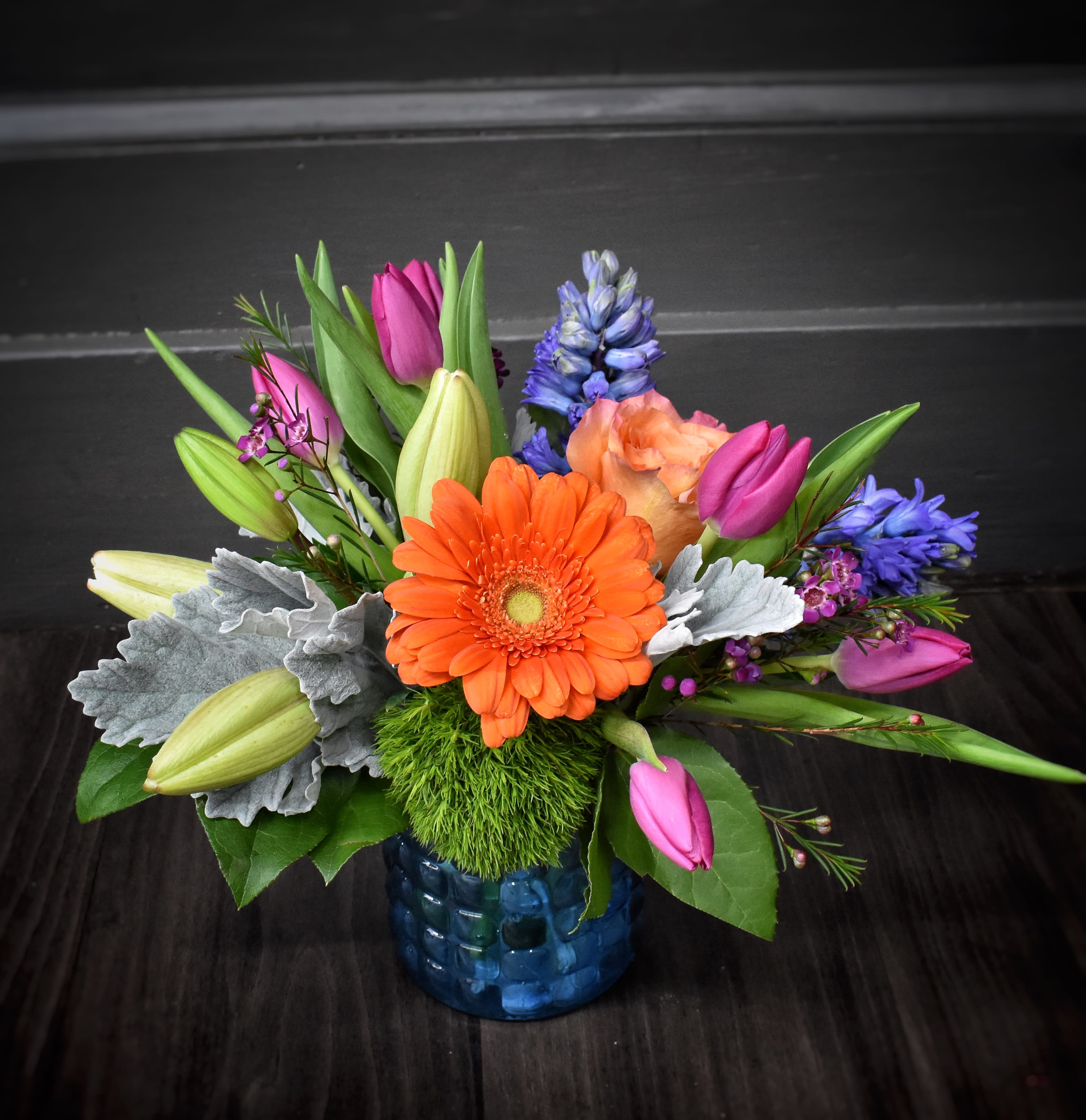 Symphony of Spring - This beautiful blue textured vase is filled with springtime blooms! Fragrant hyacinth, lilies, tulips and more, making a perfect gift.
