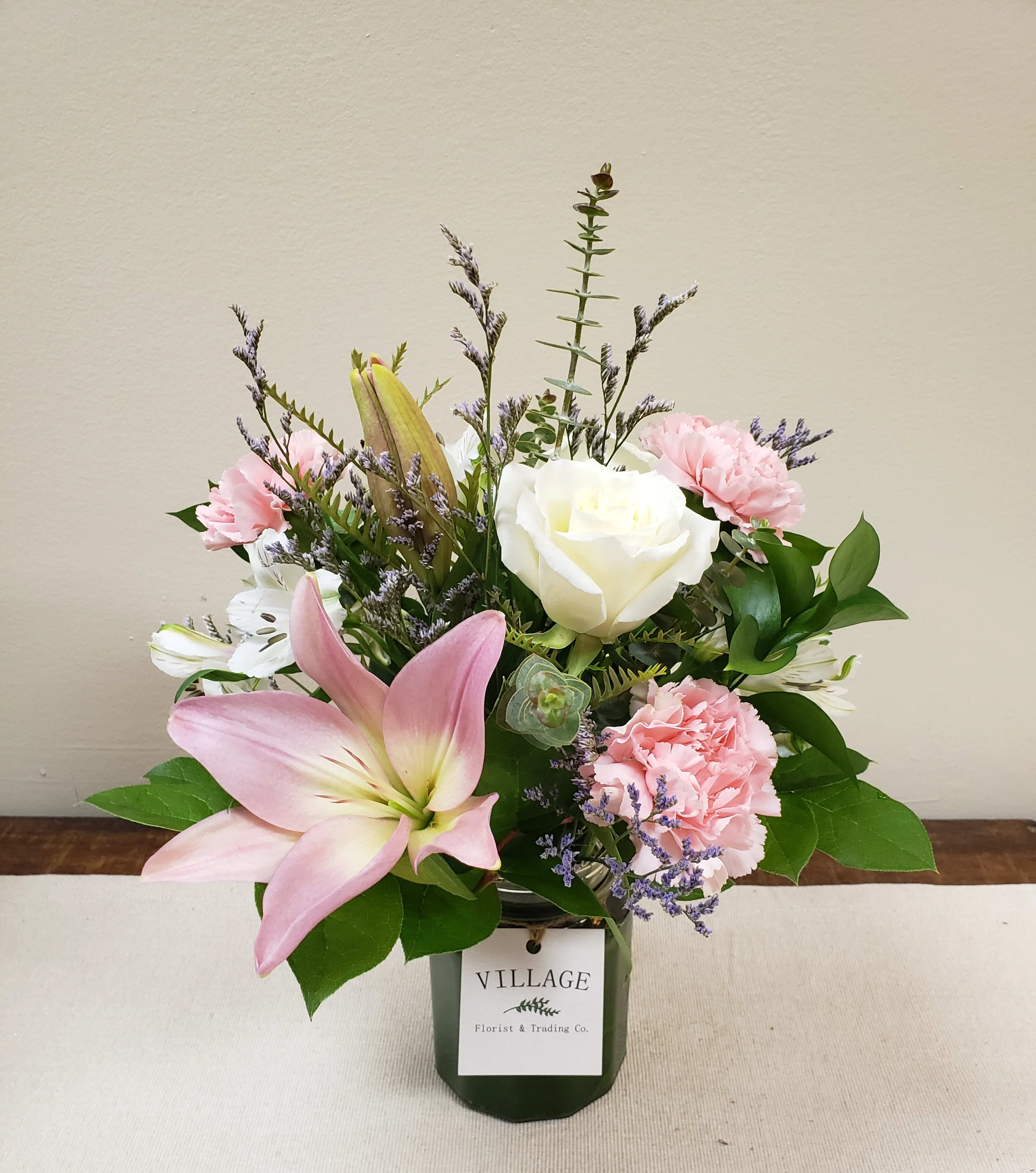 Always and Forever Collection (Modern Petite) - Always and Forever (Modern Petite) is a soft and romantic mix of pink lilies, white Alstroemeria, Pink carnations, white roses, Ruscus, Eucalyptus, Lemon Leaf and Limonium for that whimsical final touch. Tastefully arranged in a clear glass vase with an aspidistra leaf lining.