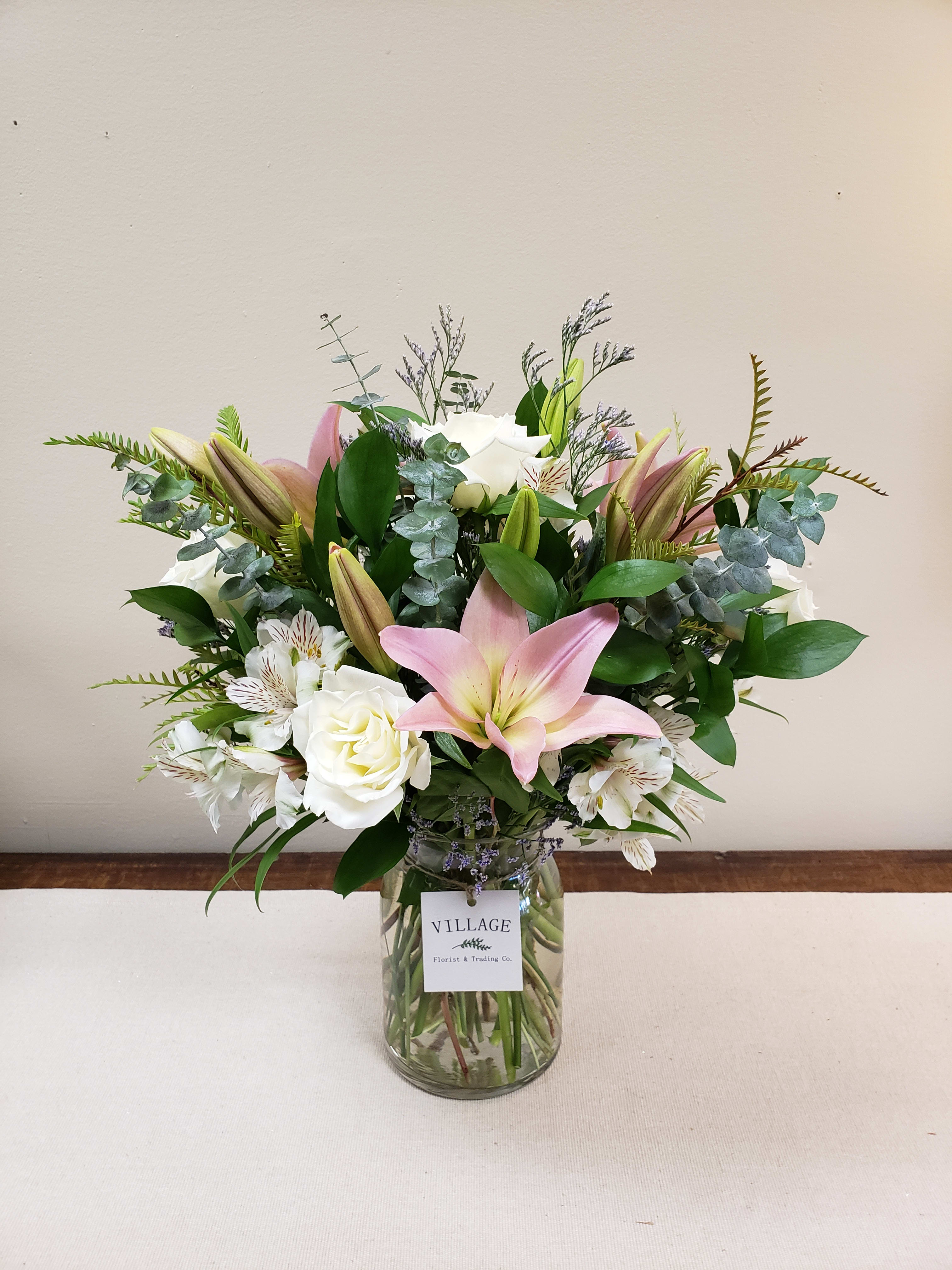 Always and Forever Collection (Grande) - Always and Forever is a soft and romantic mix of white roses, pink lilies, white Alstroemeria, Ruscus, Eucalyptus, Lemon Leaf and Limonium for that whimsical final touch. Tastefully arranged in a clear glass vase. 