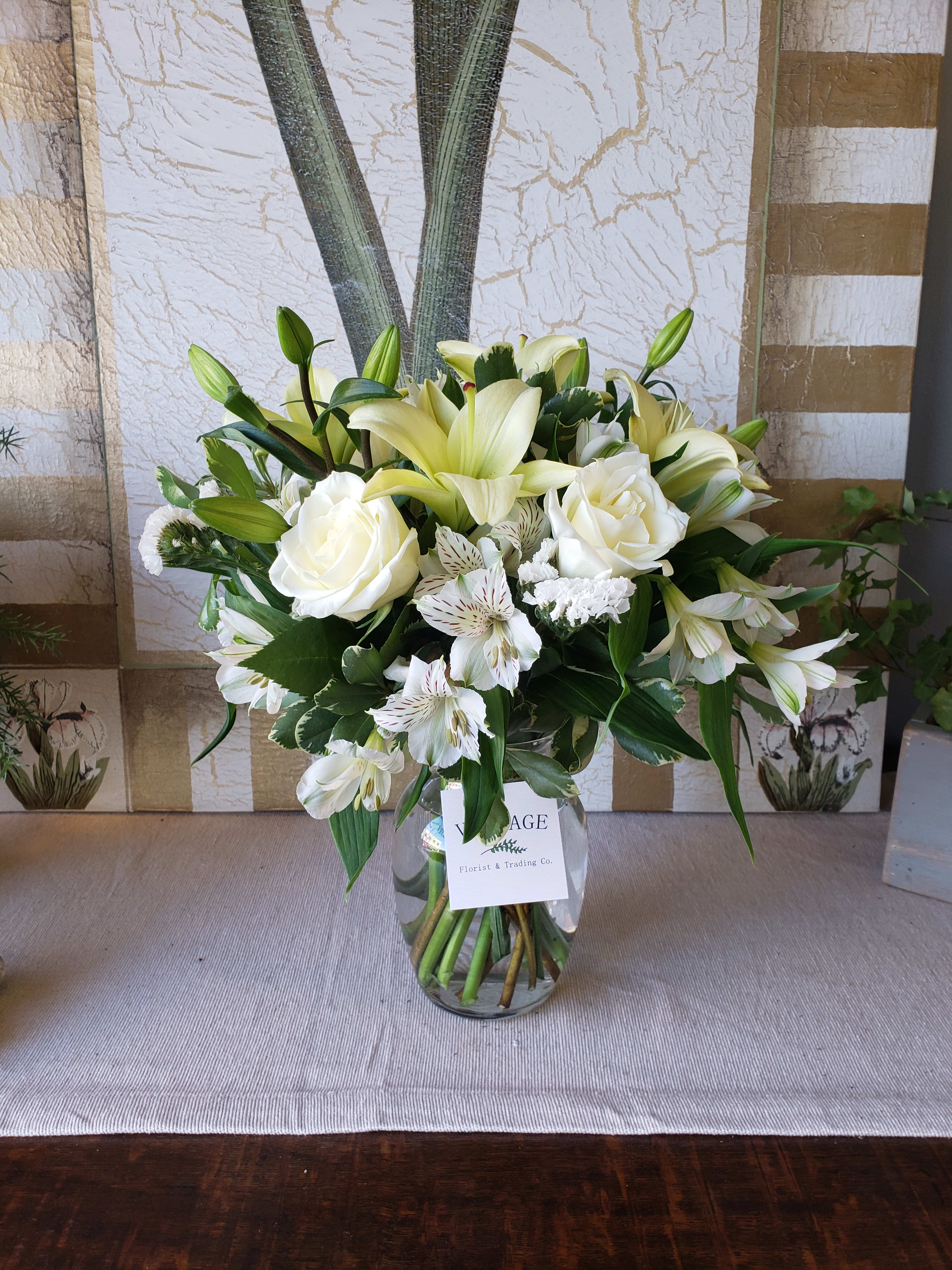 Classy - Classy is an elegant mix of white lilies, white Alstroemeria, white Statice and Classic White Roses. Tastefully arranged in a clear glass vase. 