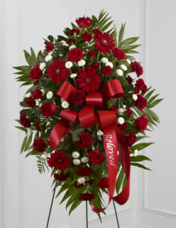 Red Royalty Standing Spray - An all red standing spray meant for royalty. Send this festive bouquet of premium red roses, red gerbera daisies, red carnations &amp; white button pompoms embeded with emerald palm to pay tribute to a departed loved one with respect and royal treatment. Hand made bow with custom banner included.  Approximately   43&quot; H x 27&quot; W